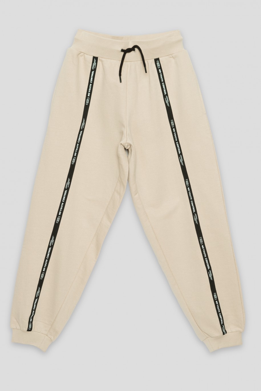 Beżowe spodnie dresowe z ozdobnymi taśmami NO YOUTH CONTROL - 37696