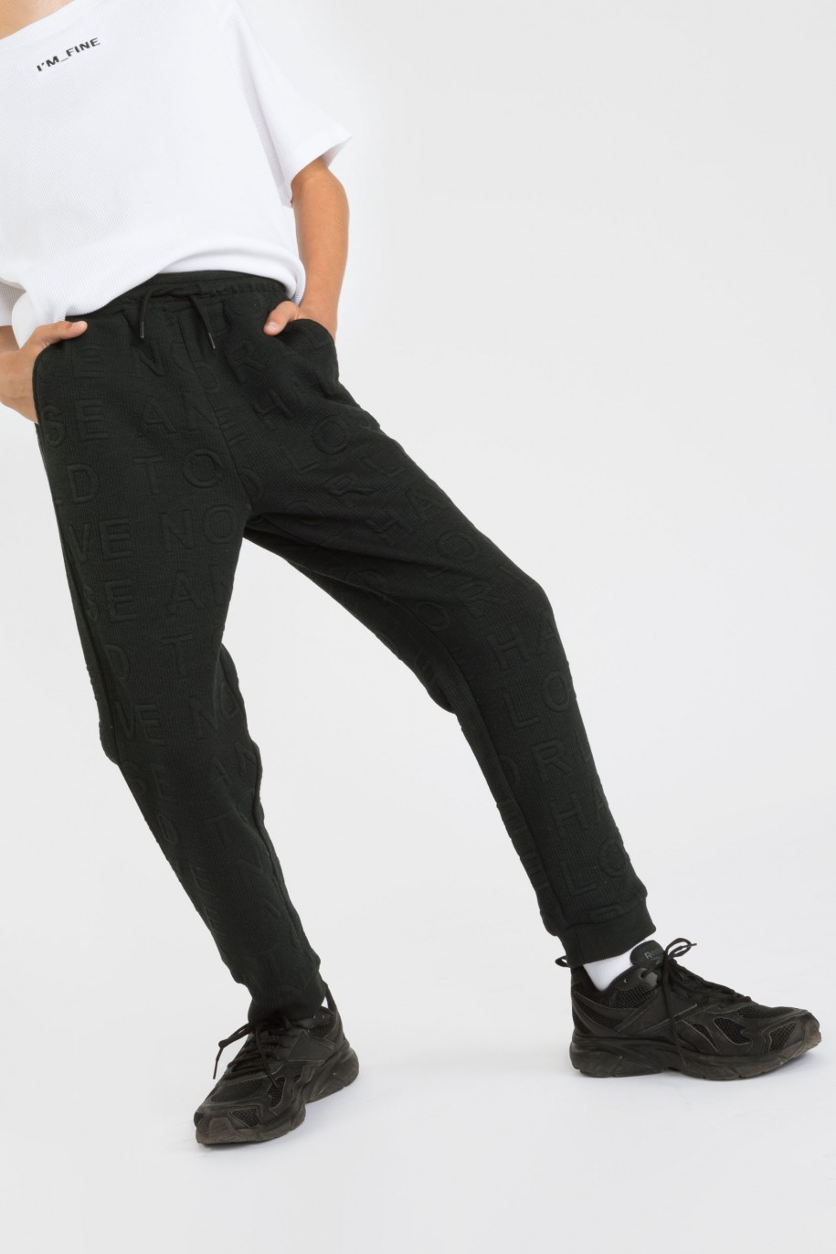 Czarne prążkowane spodnie dresowe z napisami - 38572