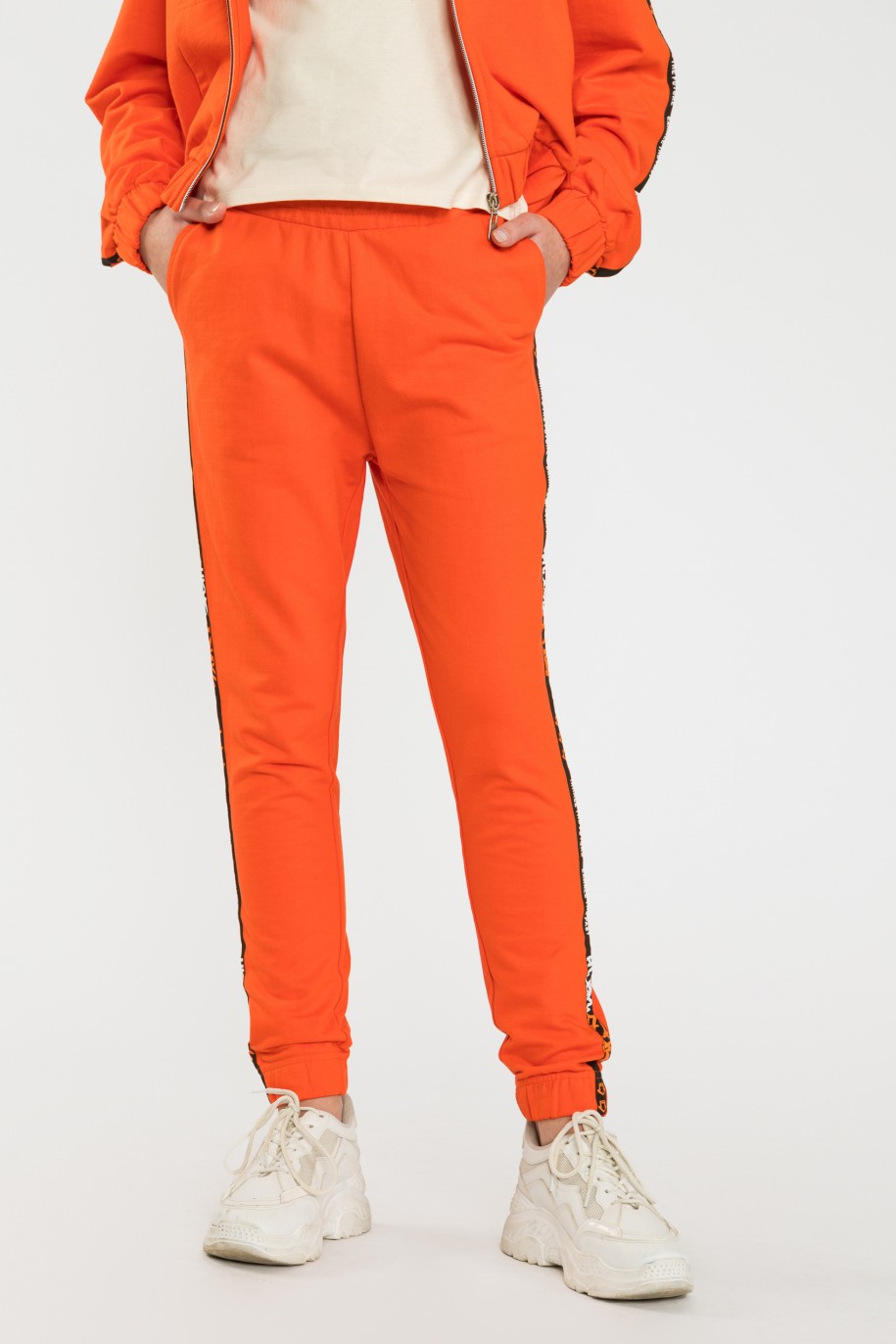 Pomarańczowe spodnie dresowe z ozdobnymi lampasami - 40513