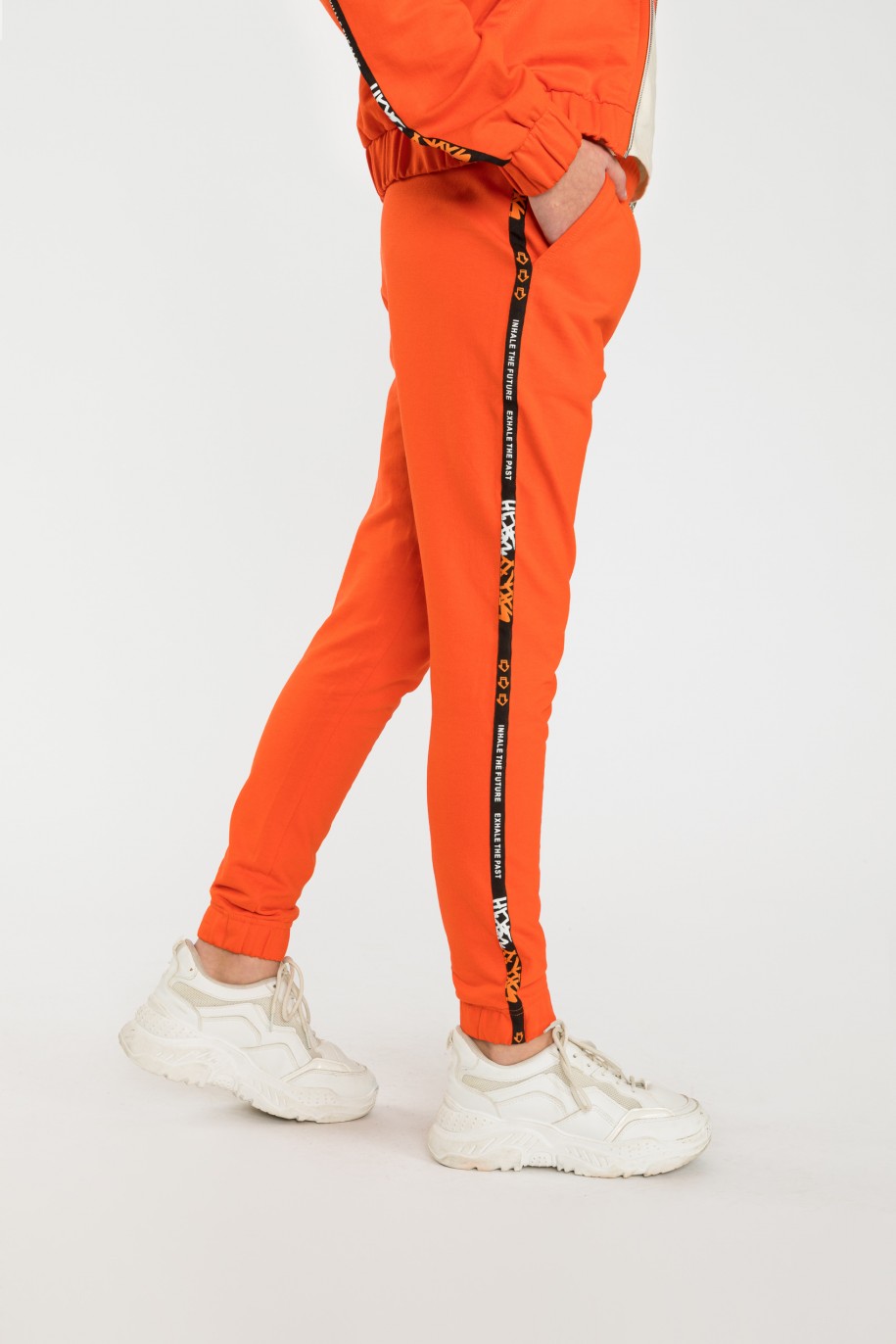Pomarańczowe spodnie dresowe z ozdobnymi lampasami - 40514