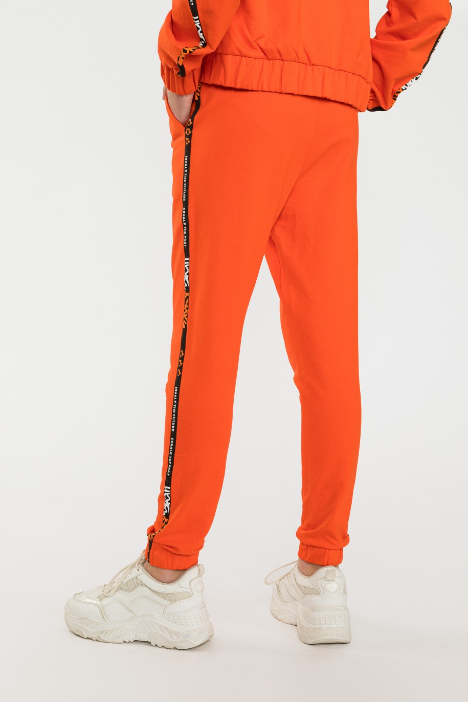 Pomarańczowe spodnie dresowe z ozdobnymi lampasami - 40515