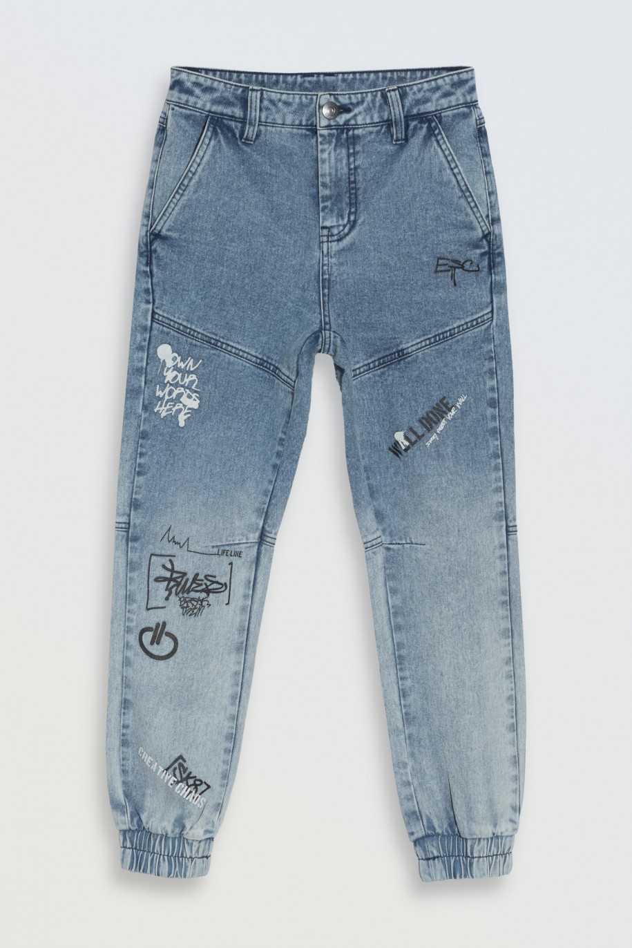 Niebieskie spodnie jeansowe typu joggery z nadrukami na nogawkach - 46553