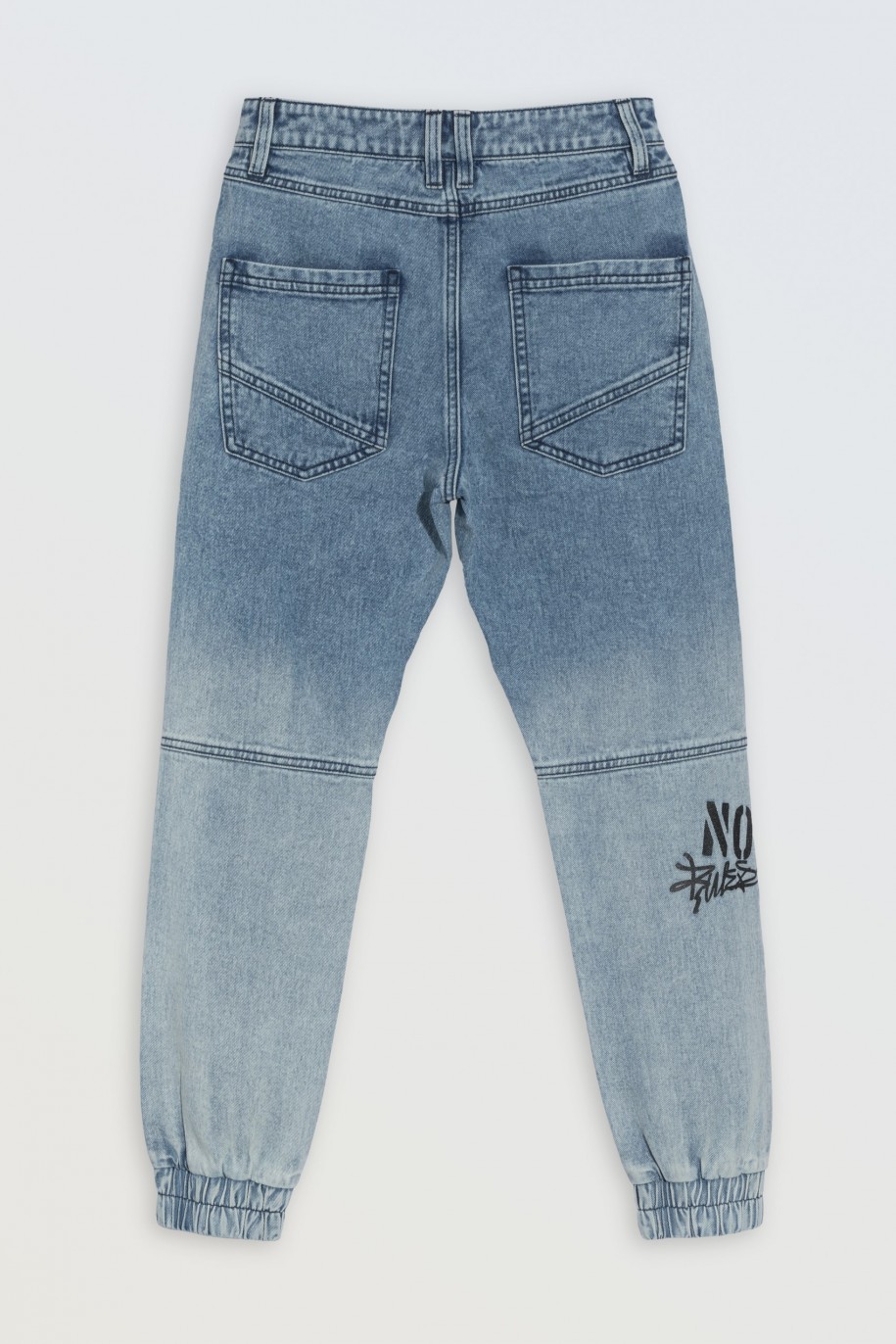 Niebieskie spodnie jeansowe typu joggery z nadrukami na nogawkach - 46554