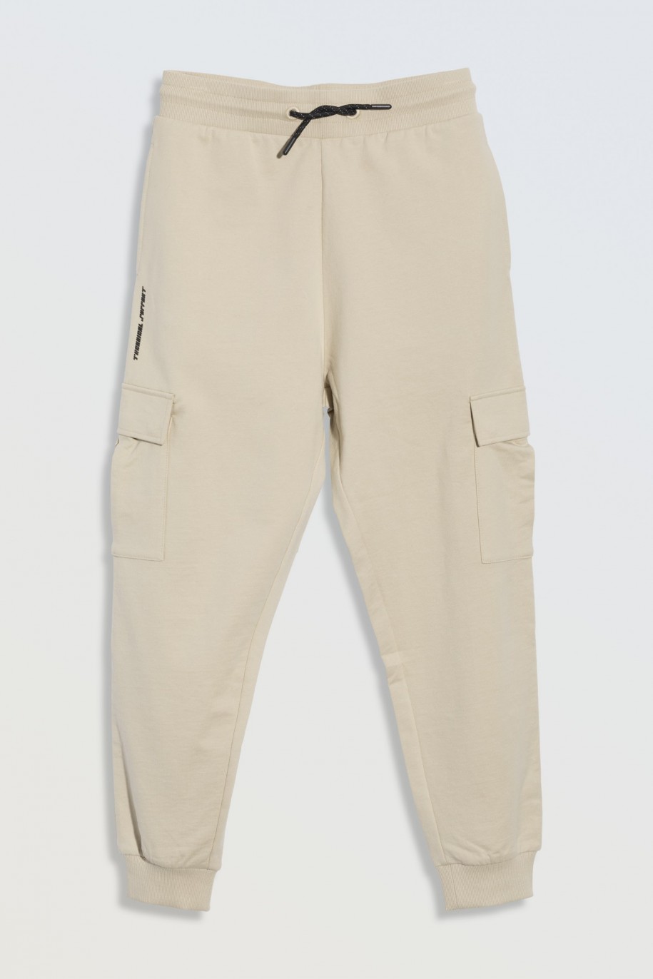 Beżowe spodnie dresowe oversize z przestrzennymi kieszeniami na nogawkach - 46843